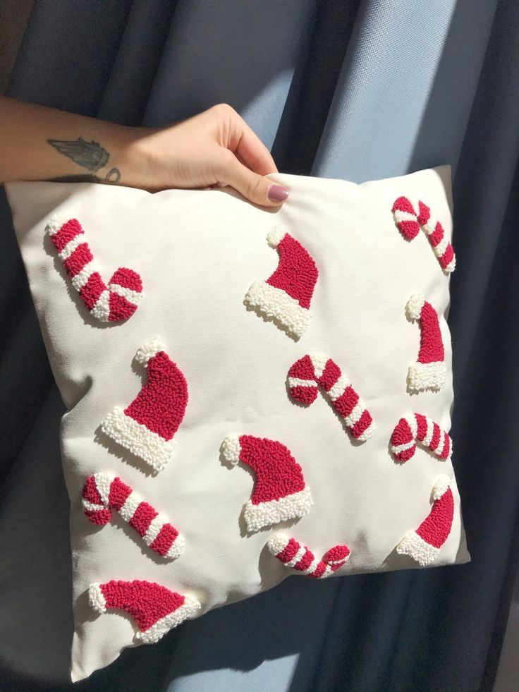 a hand holding a pillow with candy canes on it