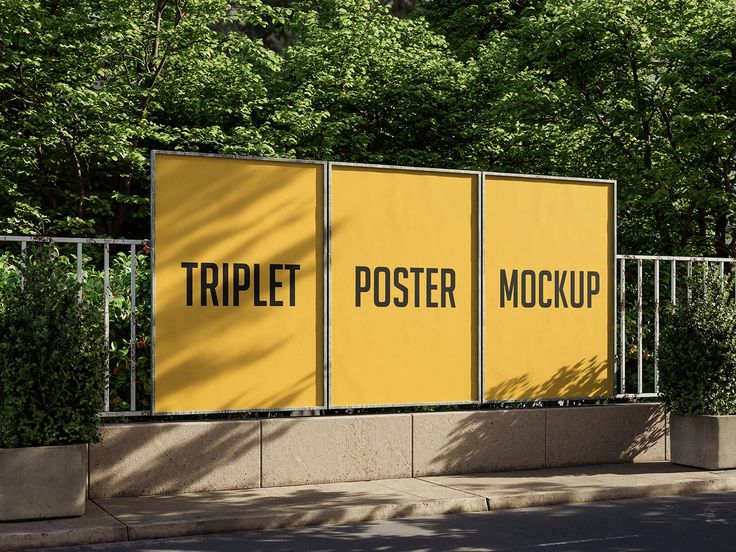 two large yellow posters on the side of a road next to a fence and trees