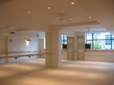 an empty room with mirrors and lights on the wall, in front of a large window