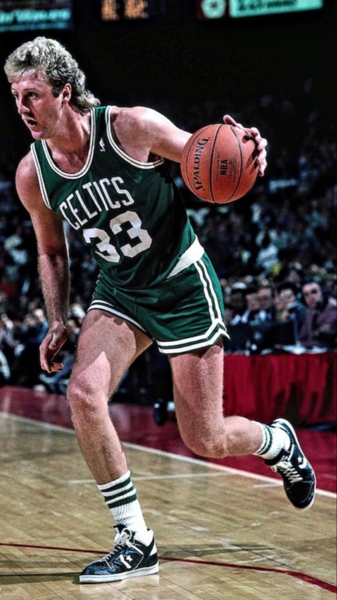 a basketball player is running with the ball in his hand while people watch from the stands