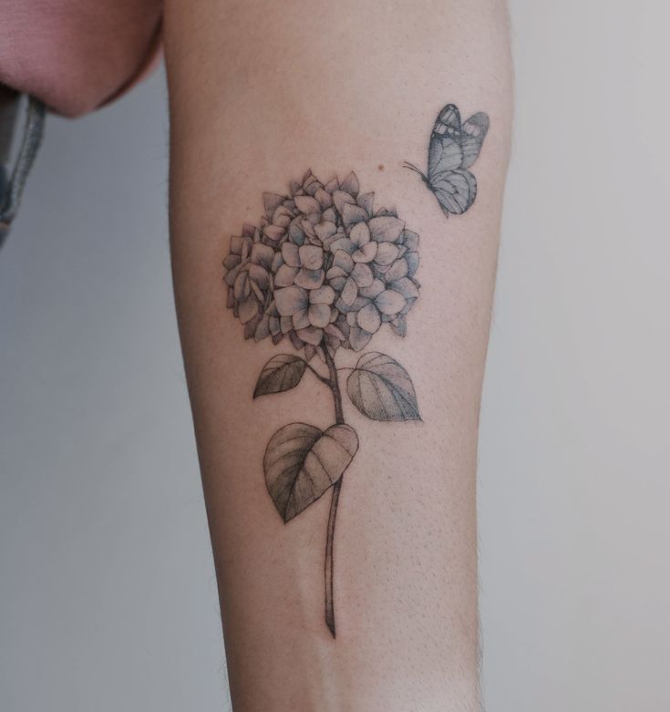 a woman's arm with a flower and butterfly tattoo on the left side of her arm