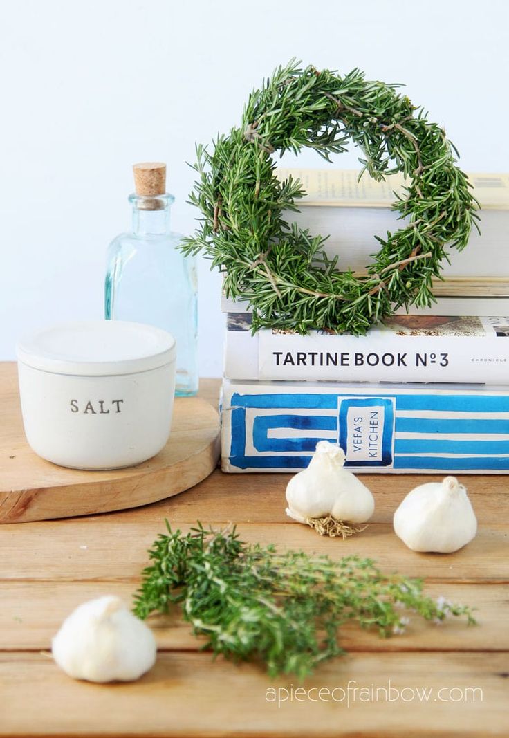 garlic and herbs on a cutting board next to books