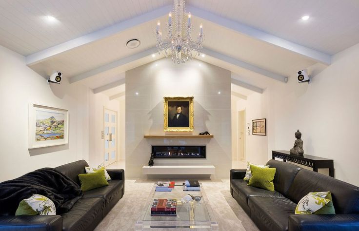 a living room filled with furniture and a chandelier hanging from the ceiling over a fire place