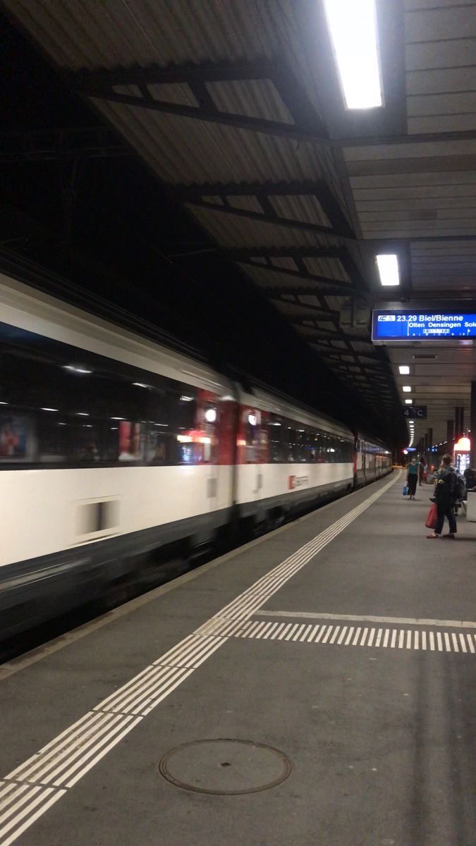 a train is coming in to the station with people walking on the platform next to it