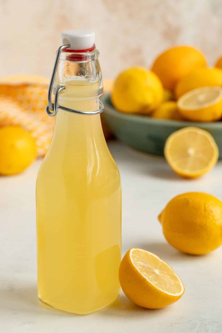 a glass bottle filled with lemonade next to sliced lemons