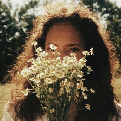 a woman holding a bunch of flowers in front of her face