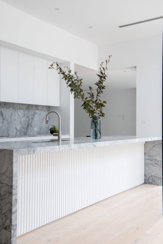 two vases filled with flowers on top of a marble counter next to a sink