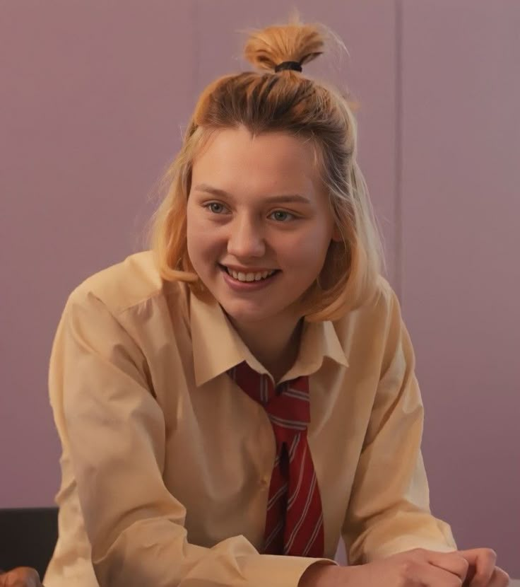 a young woman in a tie sitting at a table with her hands on the desk