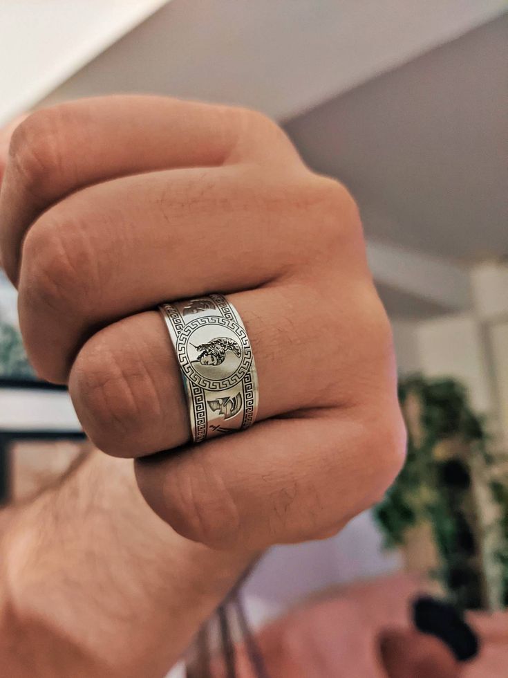 a man wearing a silver ring with money on it's side and his hand in the air