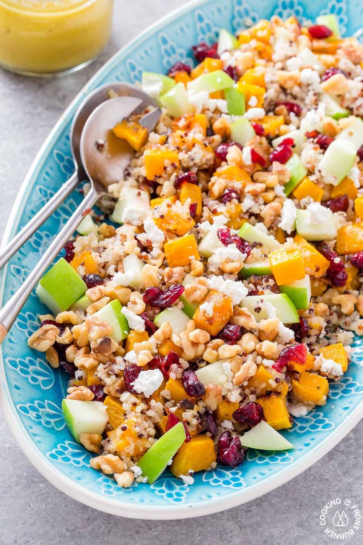 a blue bowl filled with fruit and nuts next to a glass of orange juice on the side