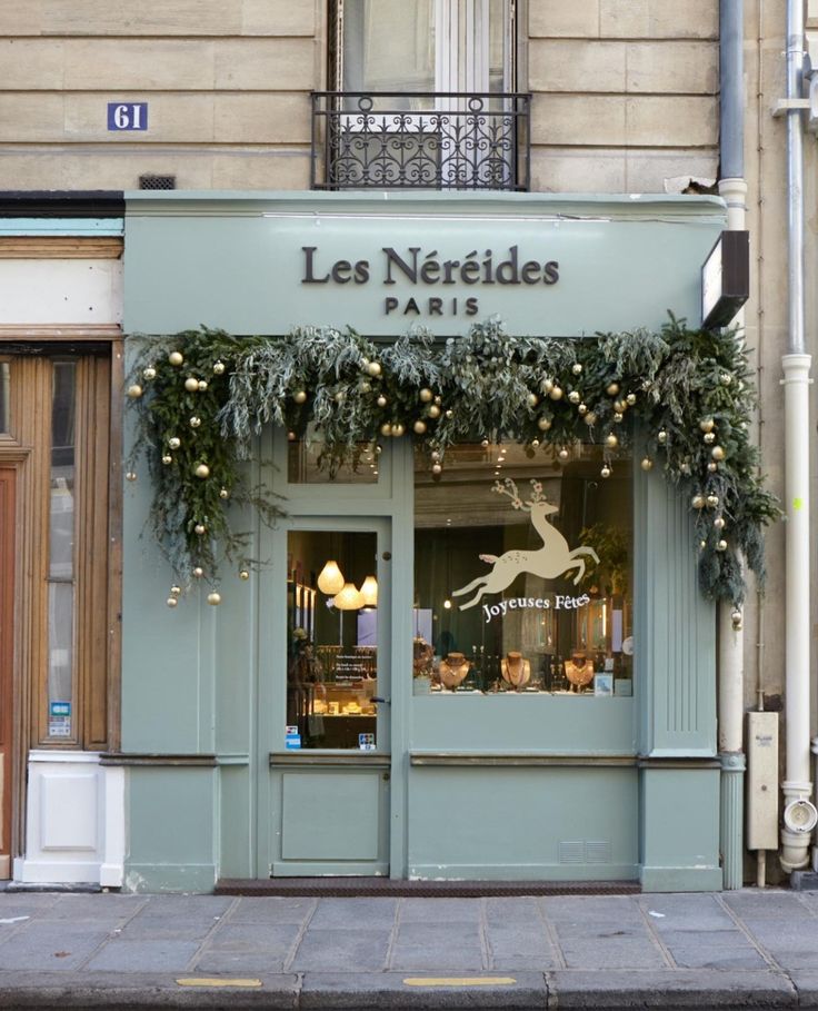 the storefront of les nerdides paris is decorated with greenery and lights