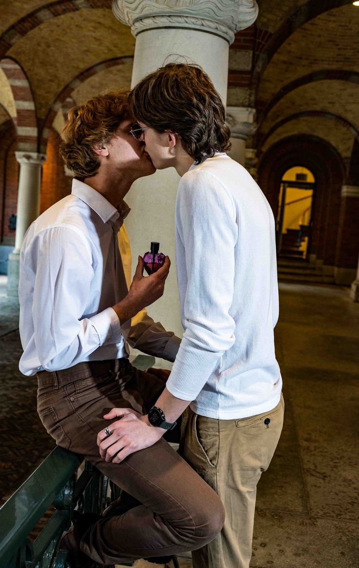 two young men are kissing each other on the balcony