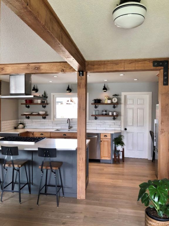 an open concept kitchen and dining room with wood flooring, white counter tops and wooden beams