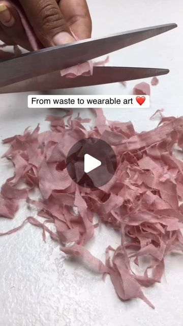 someone is cutting up pink tissue paper with scissors