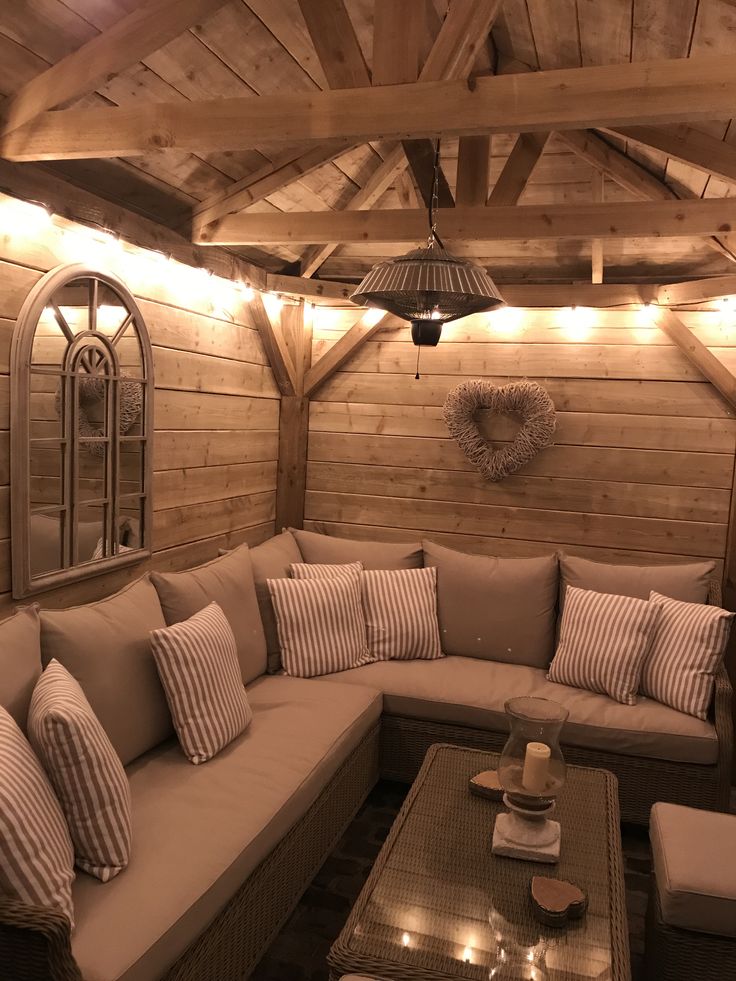 a couch and table in a room with wooden walls on the wall is lit by lights