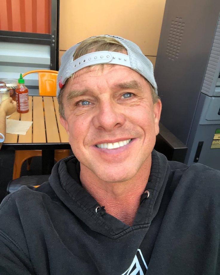 a man wearing a visor smiles at the camera while sitting in front of a table