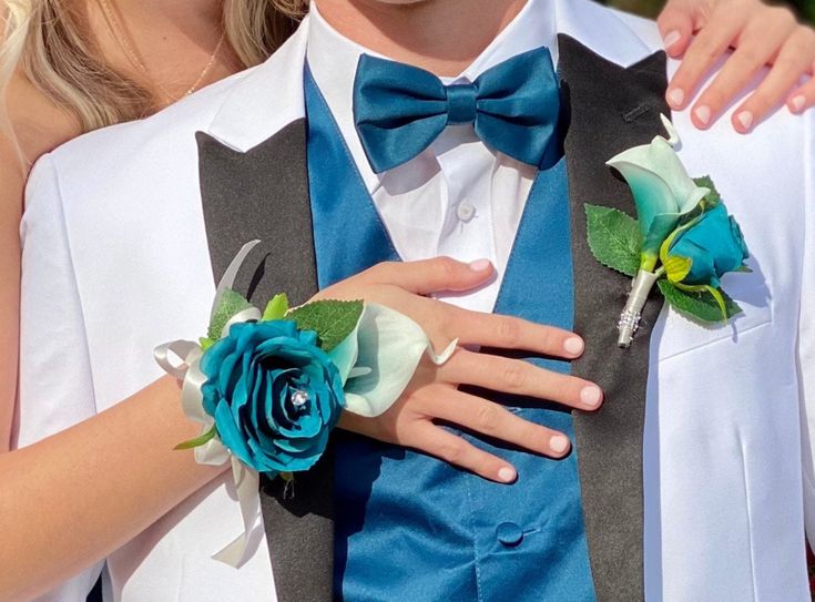 two people in tuxedos with flowers on their lapels