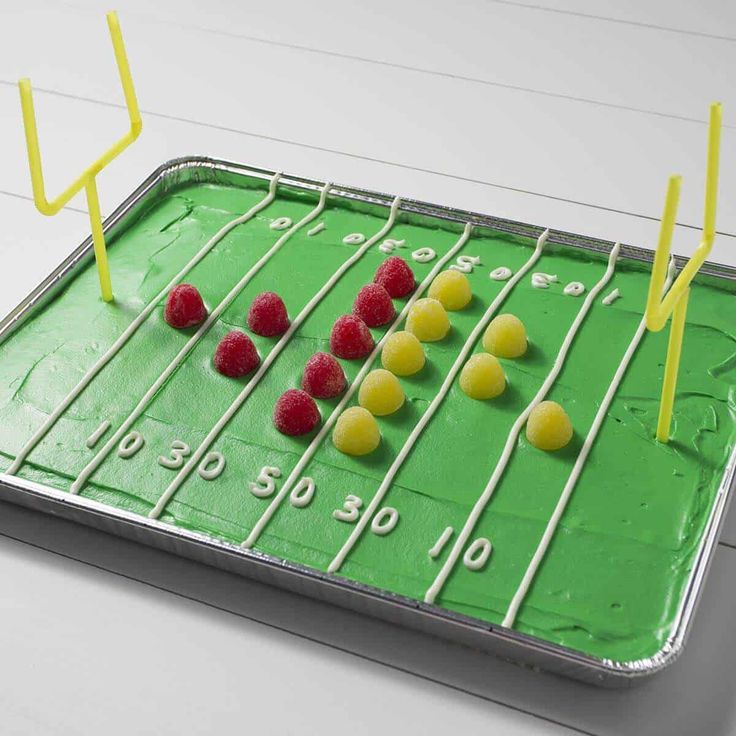 a cake shaped like a football field with yellow and red candies on the side