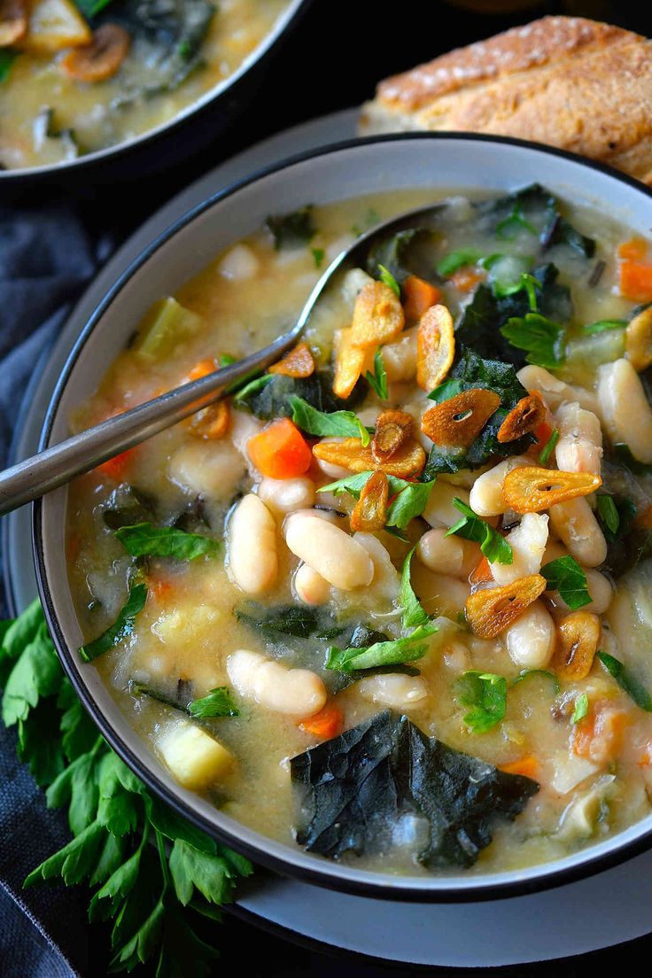 two bowls filled with soup on top of a blue cloth next to bread and vegetables