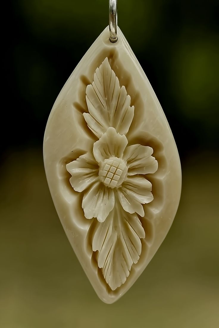 a white flower shaped pendant hangs from a chain