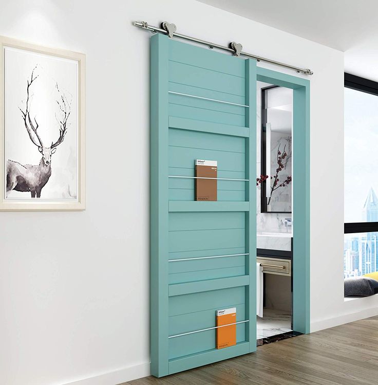 an open blue door in a white room with wood flooring and artwork on the wall