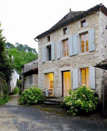 an old stone house with shutters open