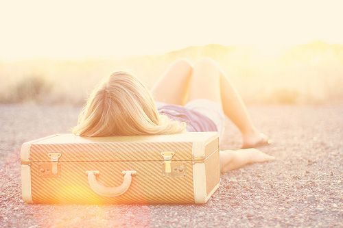 a woman laying on the floor next to a suitcase with her hair blowing in the wind