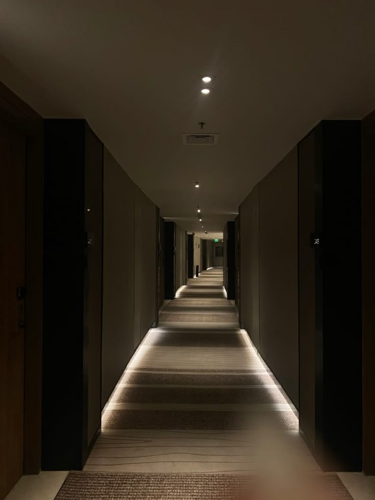 an empty hallway is lit up by recessed lights and dim lighting on the walls