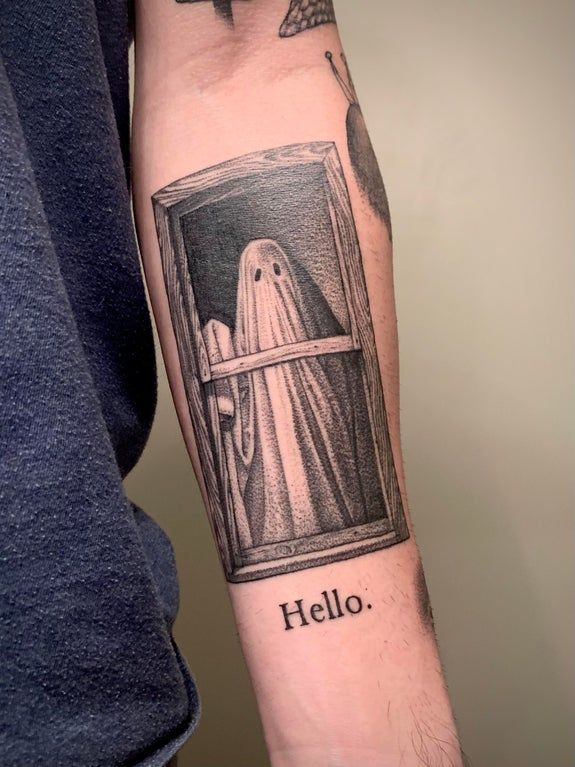 a person with a tattoo on their arm that says hello ghost in front of a window