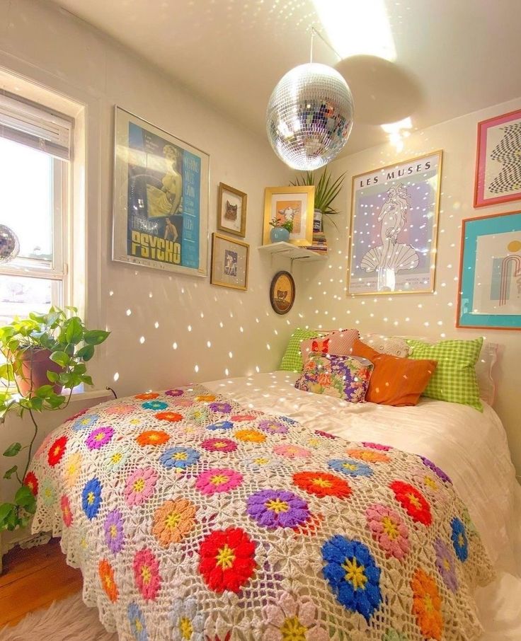 a bed with a crocheted blanket and pillows on it in a bedroom next to a potted plant