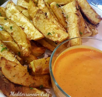 a plate with some french fries and a bowl of sauce on the side next to it