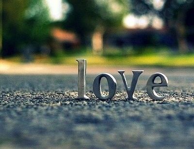 the word love is placed in the middle of an asphalt road with trees in the background