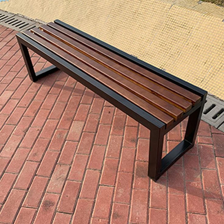 a wooden bench sitting on top of a red brick walkway next to a swimming pool