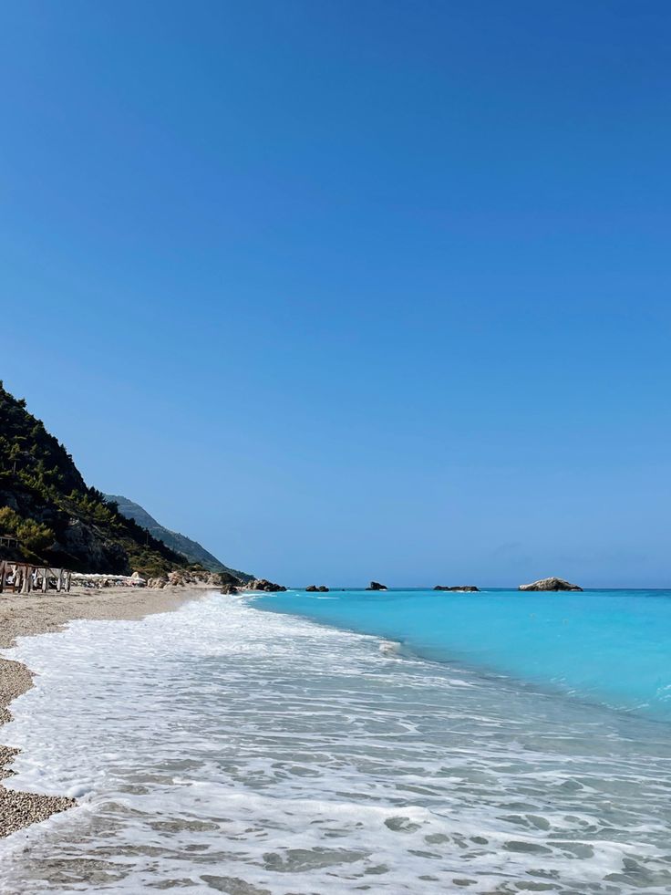 the beach is clear and blue with waves coming in