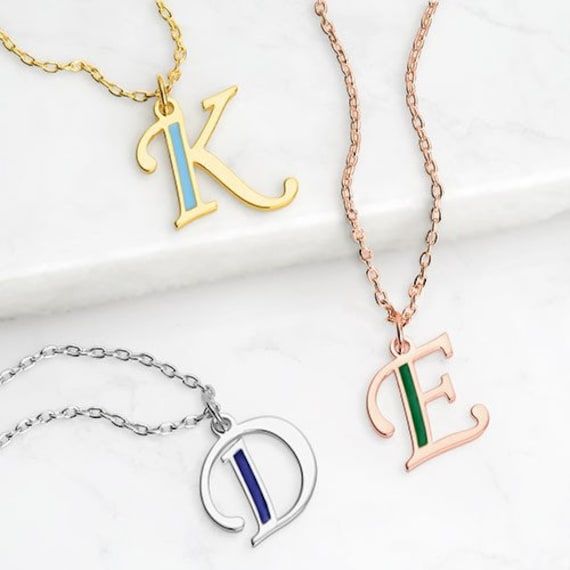 "Accent your initial with a pop of color on this stylish pendant! Script letter charm features just a touch of enamel-filled color to create a look that's fun and fashionable. Select a birth month color or favorite hue to craft a beautiful gift for yourself or someone special. Available in three metal colors; glittering Gold, shimmering Silver or radiant Rose Gold. Personalization cannot contain any special characters, emojis or shapes. Images and designs are registered with the USPTO to Persona Anniversary Pendant Necklace In Enamel, Personalized Enamel Necklaces, Enamel Initial Pendant Jewelry Gift, Birth Month Colors, Letter-shaped Monogram Necklaces For Anniversary, Personalized Gold-tone Initial Pendant Necklace, Script Initial, Shapes Images, Letter Charm