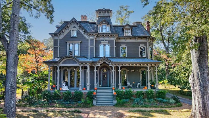 a large gray house surrounded by trees and bushes