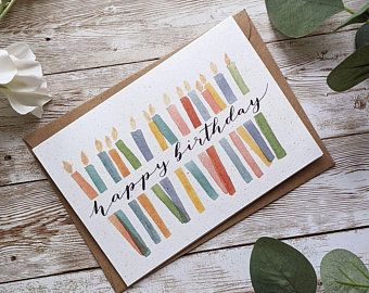 a birthday card with candles on it and some flowers next to it, which reads happy birthday