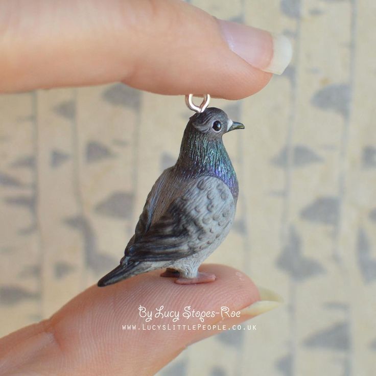 a tiny bird sitting on top of a person's finger with a ring around it's neck