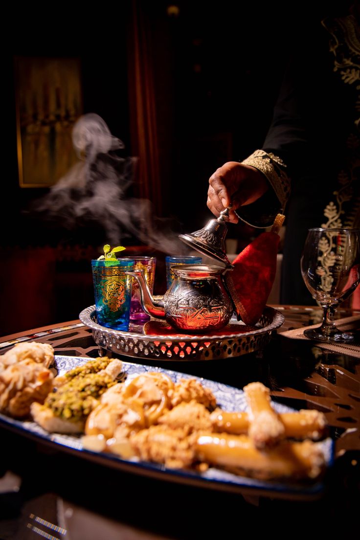 a person pouring tea on top of a tray filled with fried food and other foods