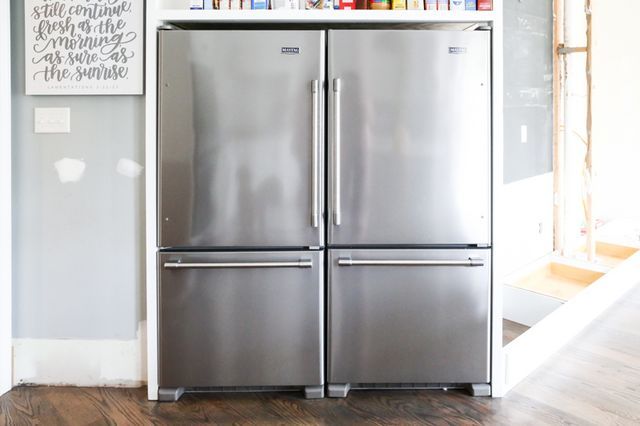 two stainless steel refrigerators sitting in front of a book shelf with books on it