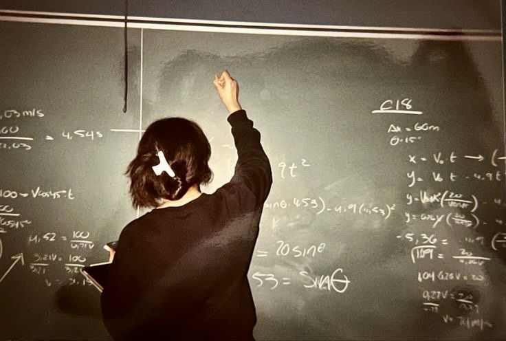 a woman writing on a blackboard with chalk