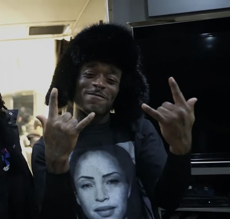 a man in a fur hat is making the peace sign with his hands while standing next to another man