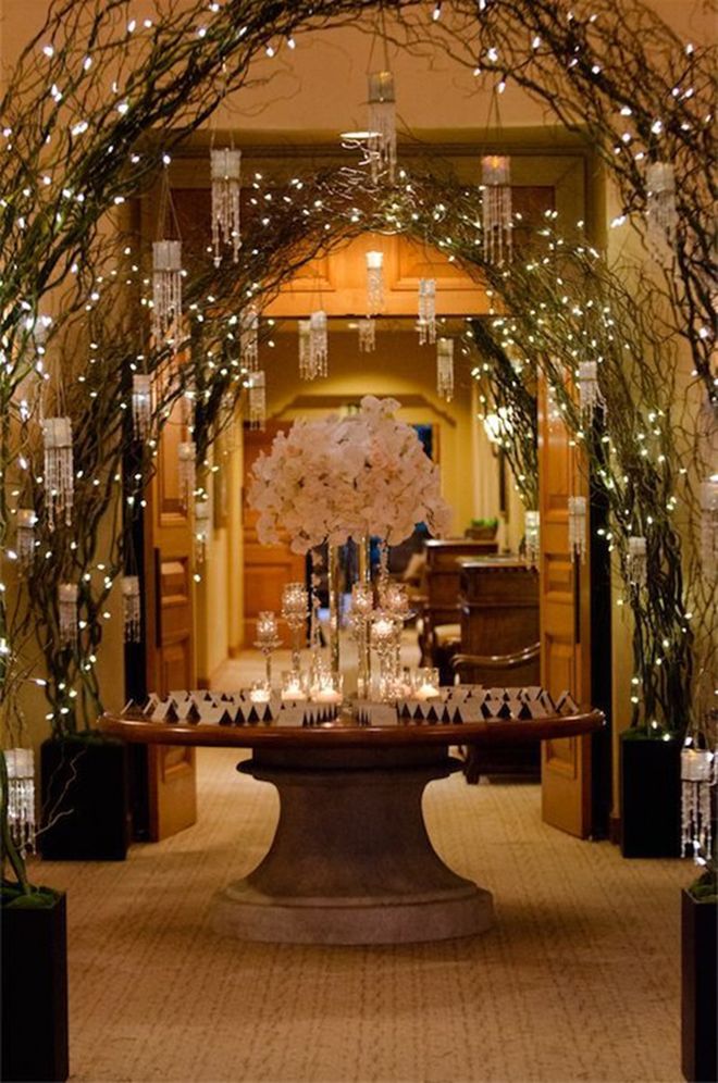 an archway decorated with branches and candles for a formal function at the reception hall or venue