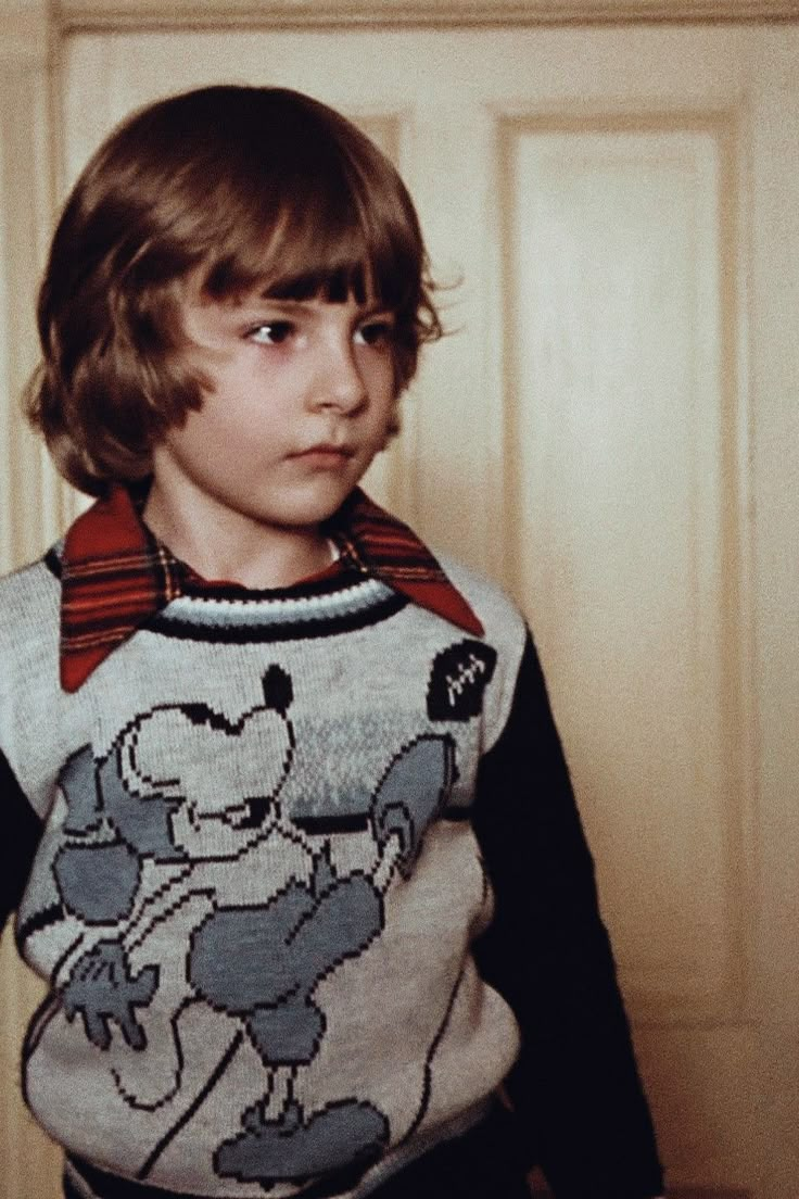 a young boy wearing a sweater with an animal on it