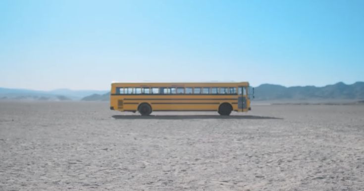 a yellow school bus driving through the desert