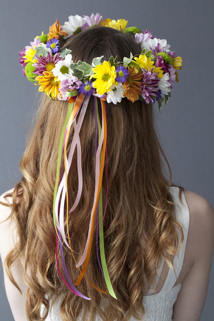 a woman with long hair wearing a flower crown on her head and colorful streamers in her hair