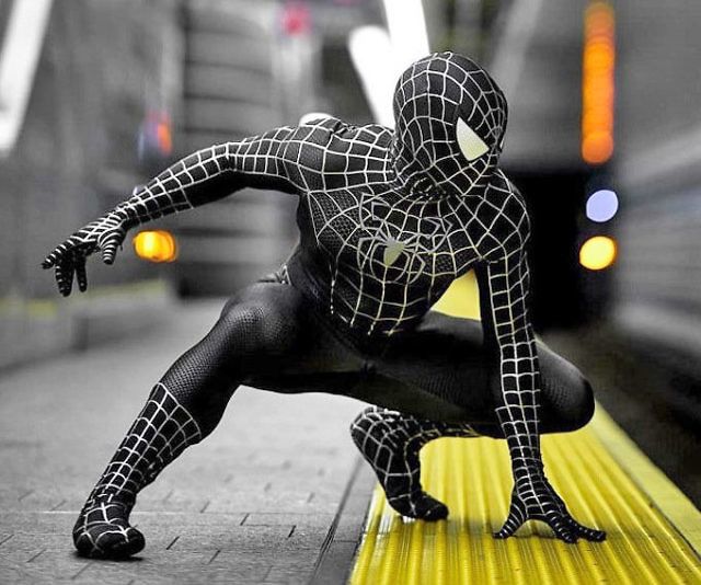 a man in a spider suit poses on a subway platform