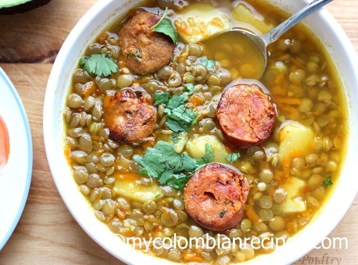 two bowls filled with soup and vegetables on top of a wooden table