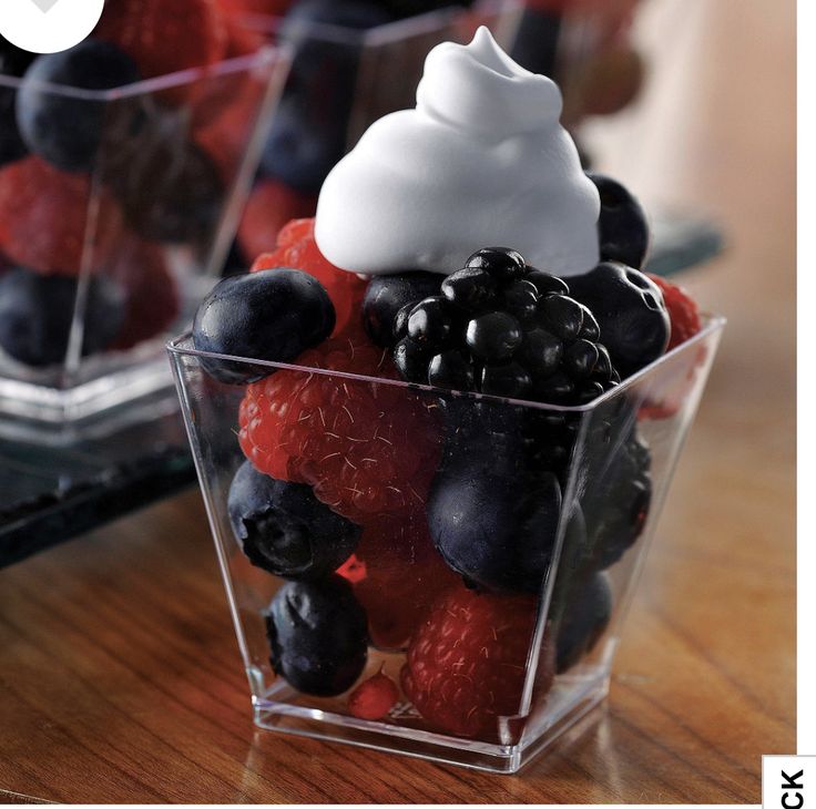 berries, raspberries and blueberries in a plastic container on a wooden table