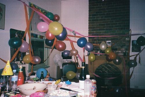 a party with balloons and confetti on the table in front of a fireplace